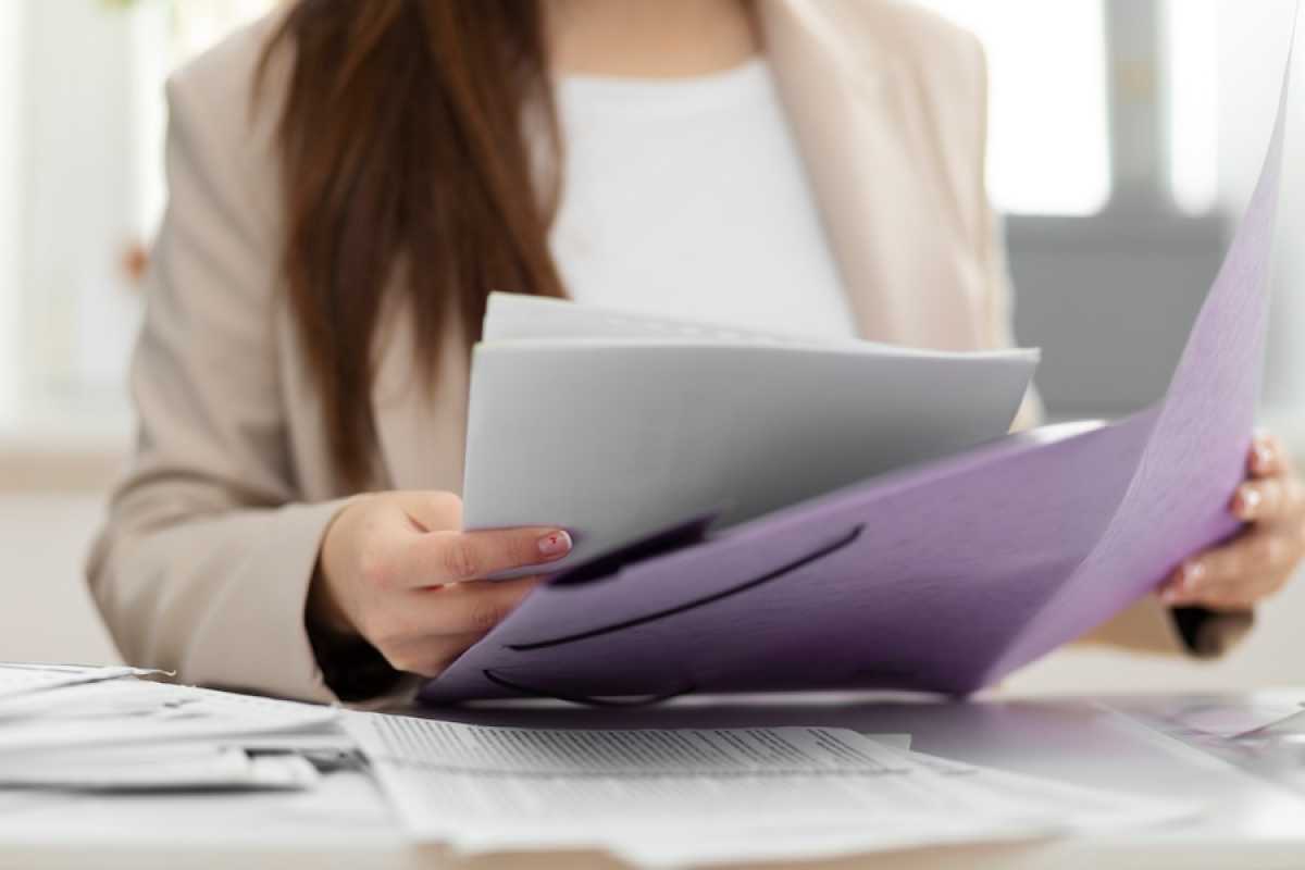 Mujer que revisa papeles en una carpeta sobre su escritorio