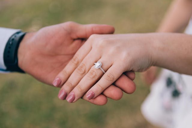 Mano de mujer con un anillo de compromiso de diamante sobre la mano de su pareja