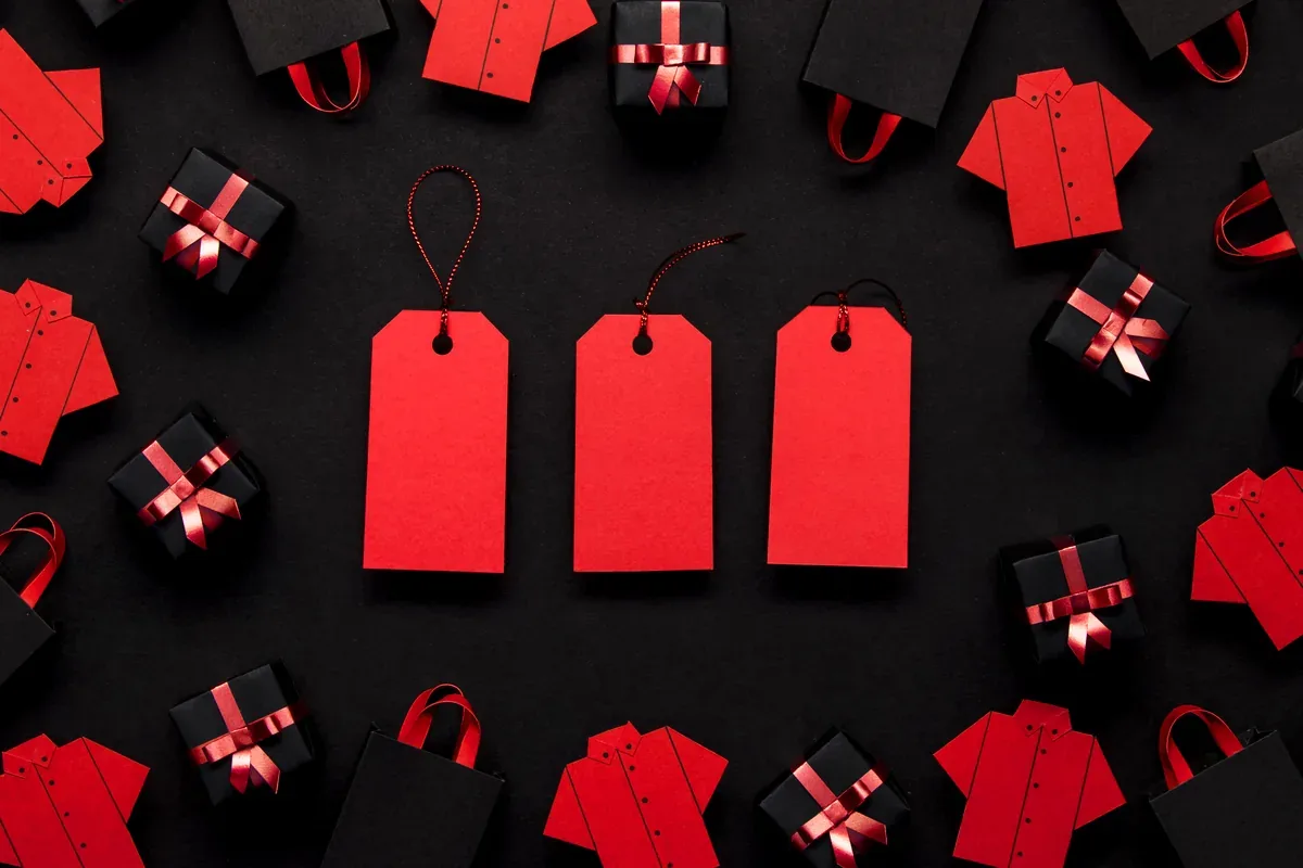 Etiquetas de precio rojas, bolsas de regalo y camisas de papel sobre fondo negro