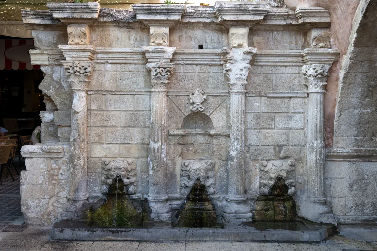Fuente de piedra antigua con columnas y tres caños