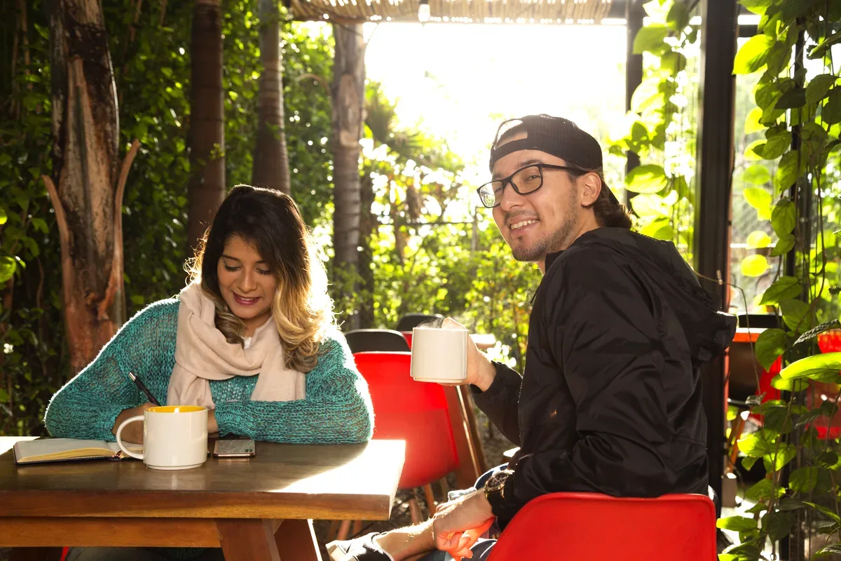 Mujer y hombre que toman café en una terraza con plantas