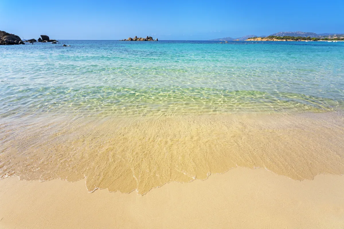 Orilla de una playa de arena con agua cristalina