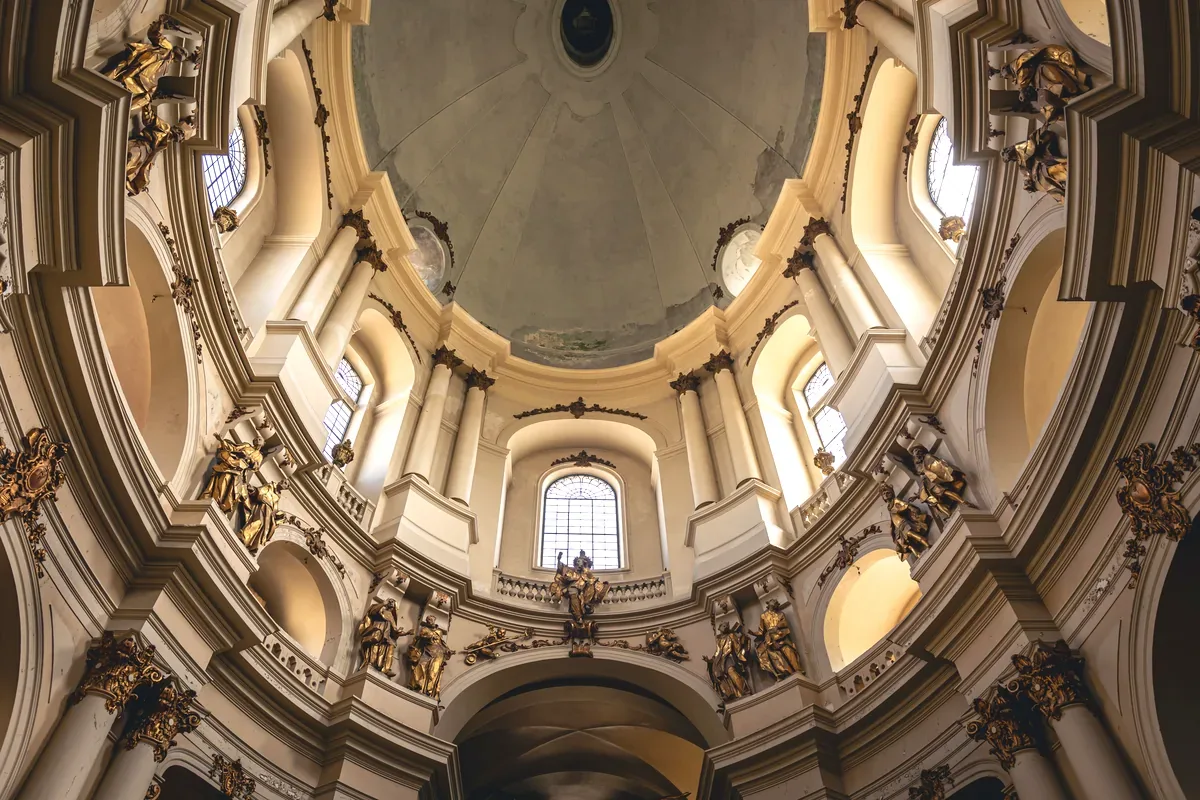 Interior de una cúpula barroca con ventanas y decoración dorada