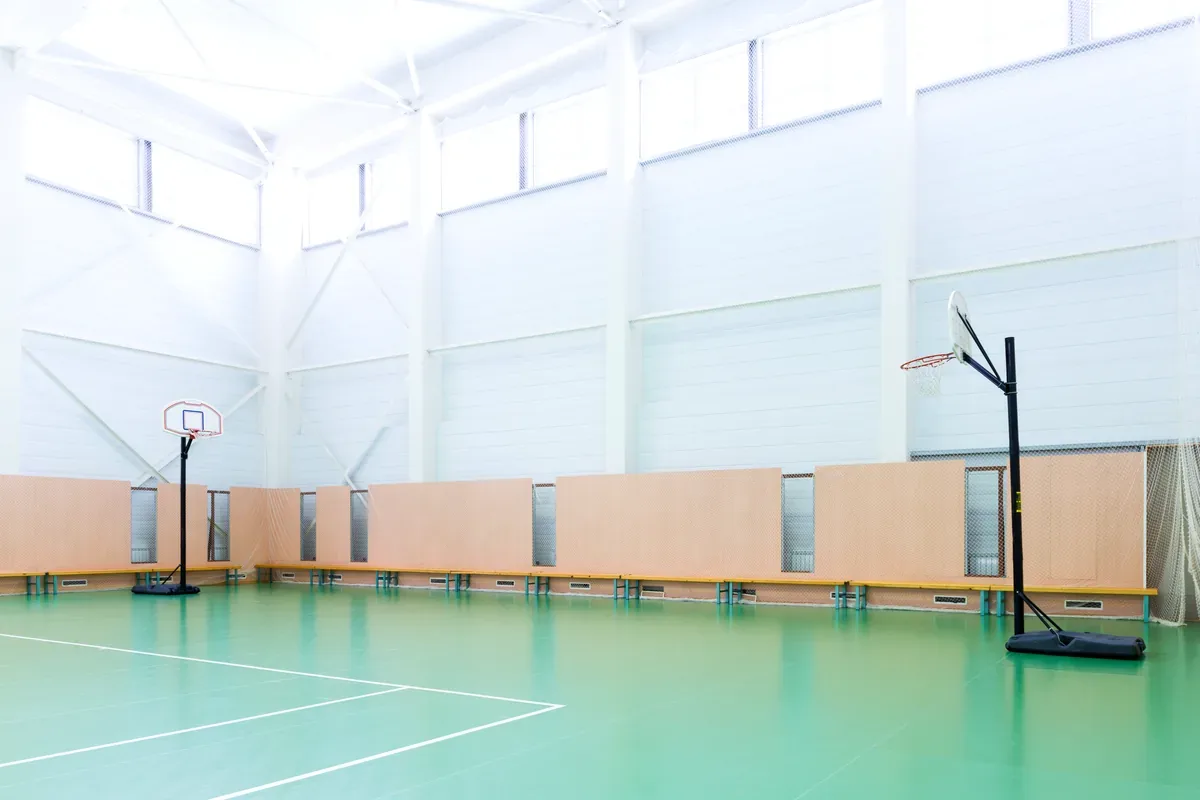 Gimnasio cubierto vacío con piso verde y aros de básquet