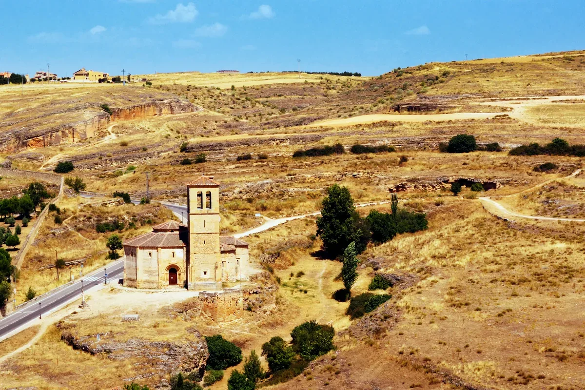 Iglesia de piedra con torre en un paisaje seco de colinas
