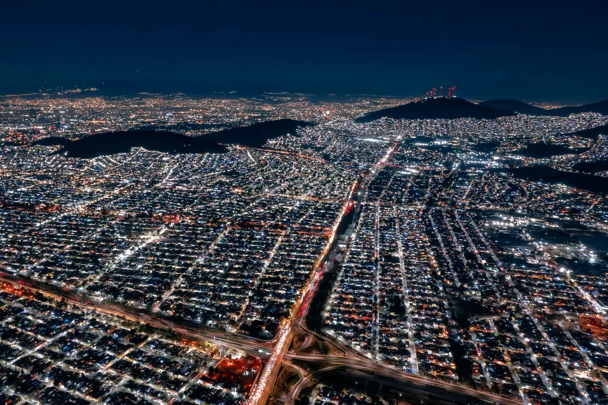 Vista aérea nocturna de una gran ciudad iluminada entre montañas