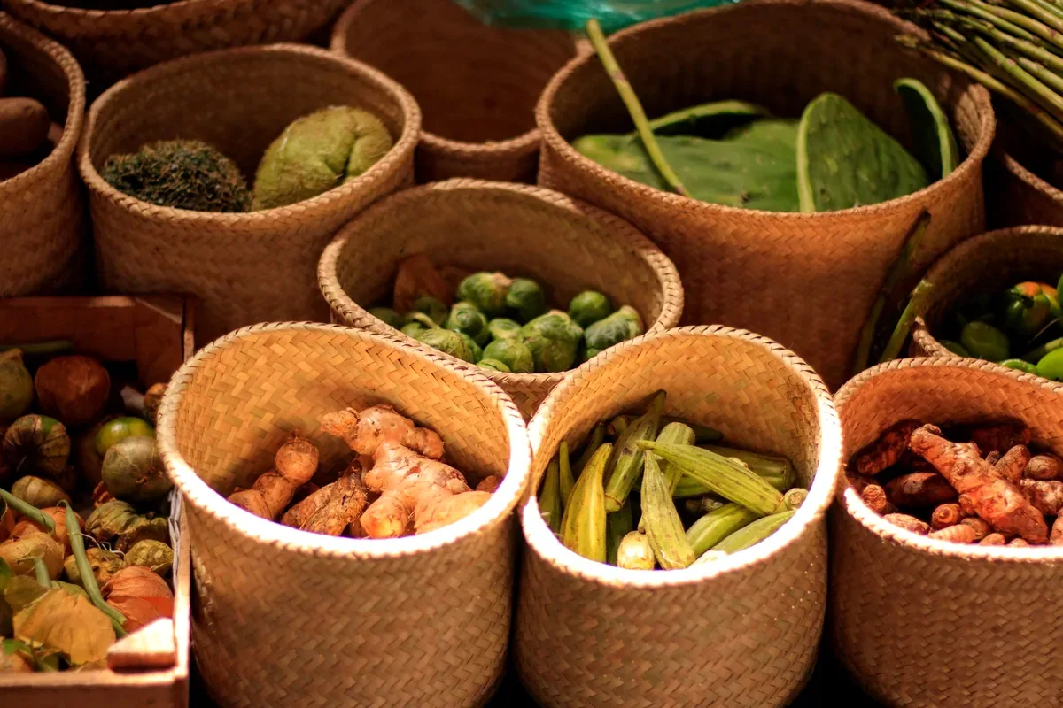 Canastos de mimbre con chiles, nopales, cúrcuma y otras verduras en un mercado