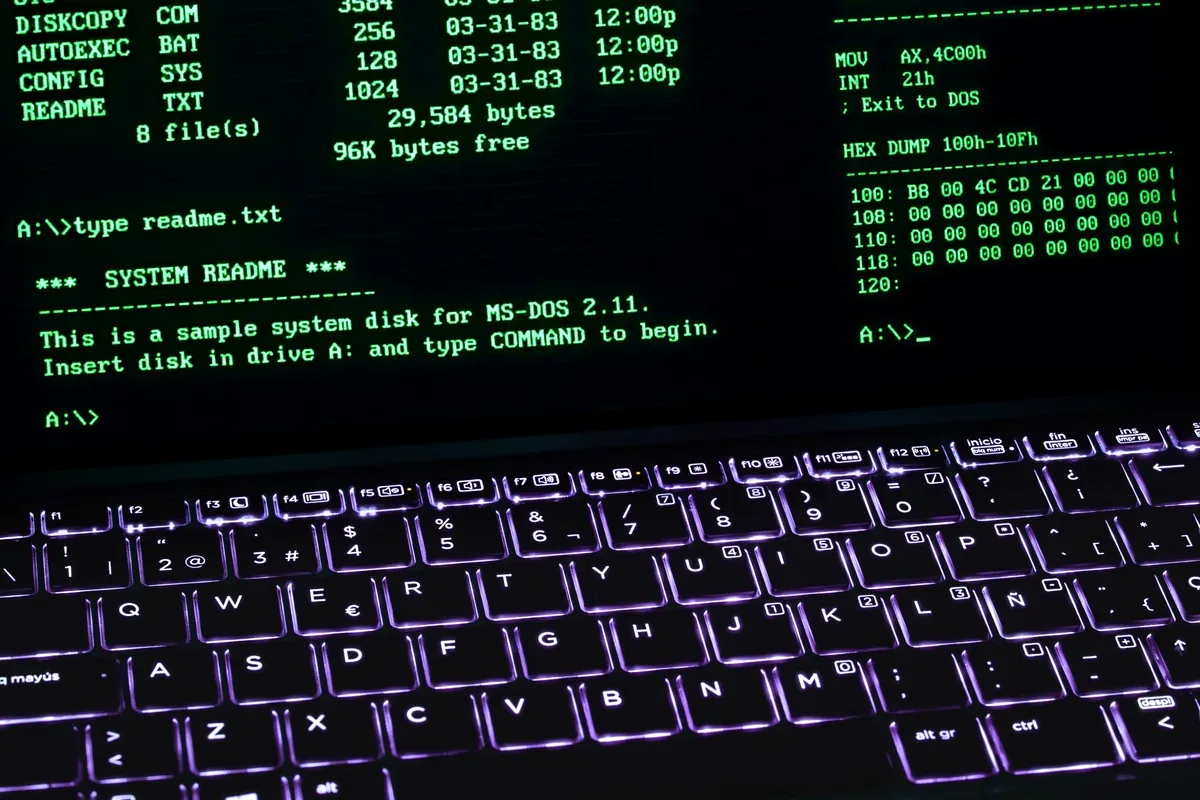 Pantalla con texto de MS-DOS sobre un teclado iluminado
