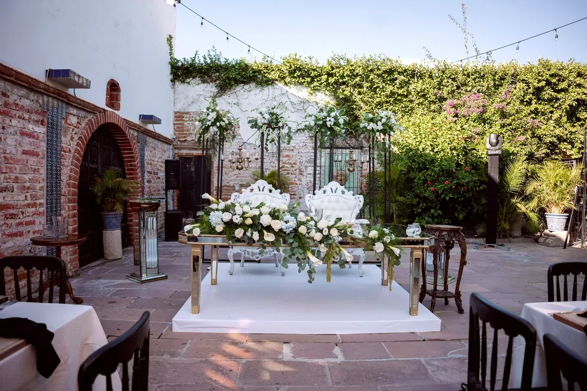 Patio con una mesa de novios decorada con flores blancas