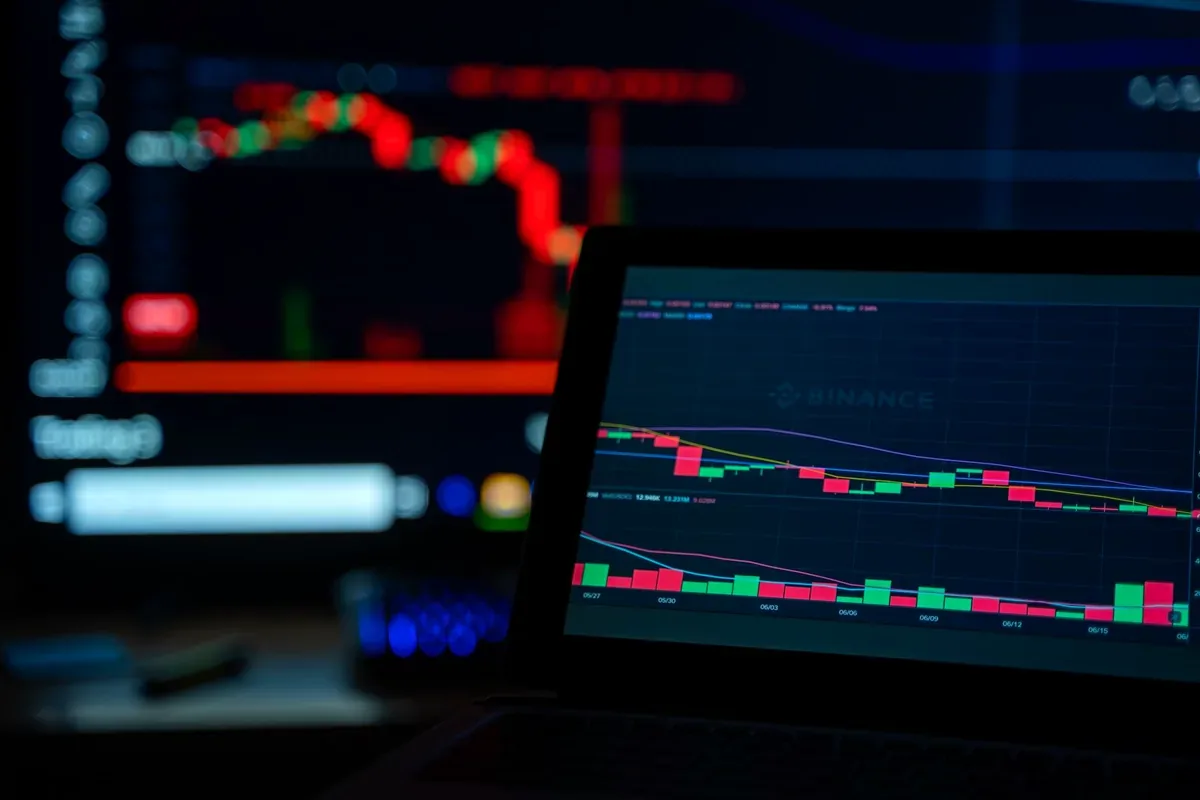 Computadora portátil y monitores con gráficos de cotizaciones en rojo y verde