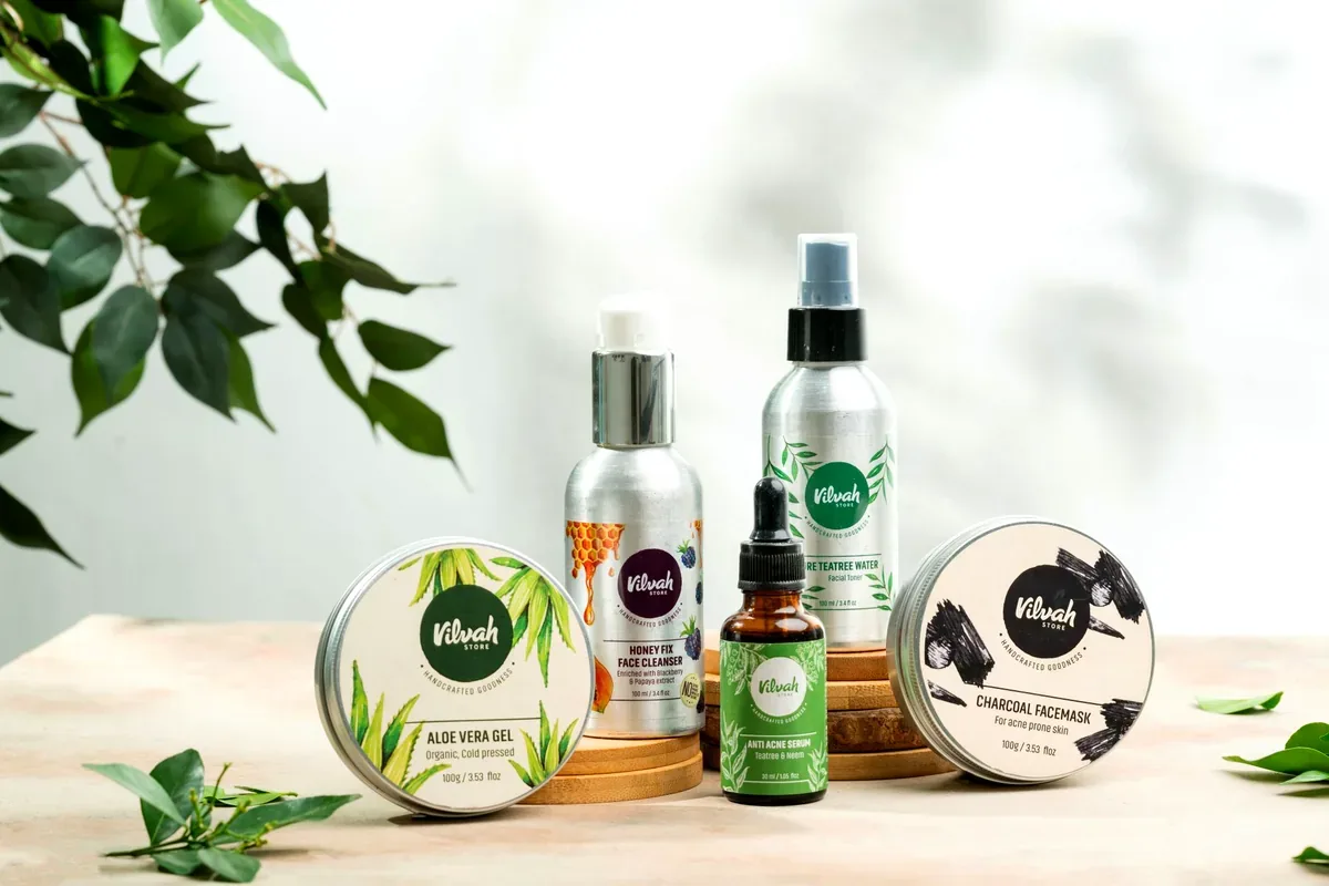 Productos de cuidado del cabello y la piel sobre una mesa de madera con hojas verdes