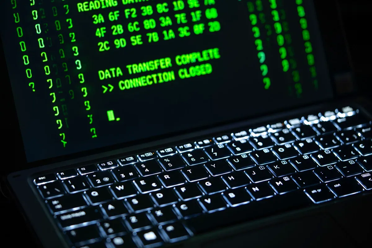 Computadora portátil con texto de código verde en la pantalla y el teclado iluminado