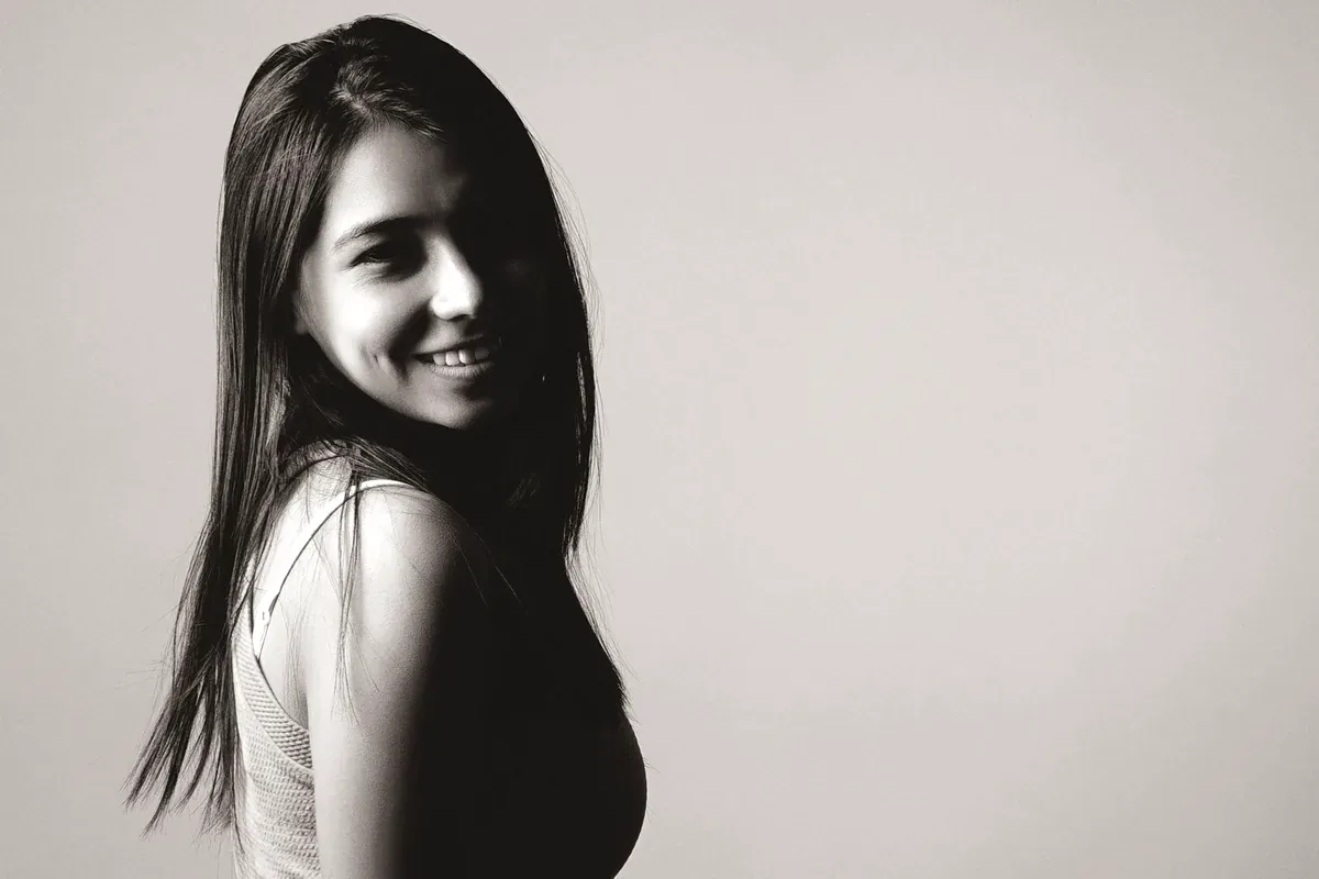 Mujer sonriente de cabello largo y lacio, en blanco y negro