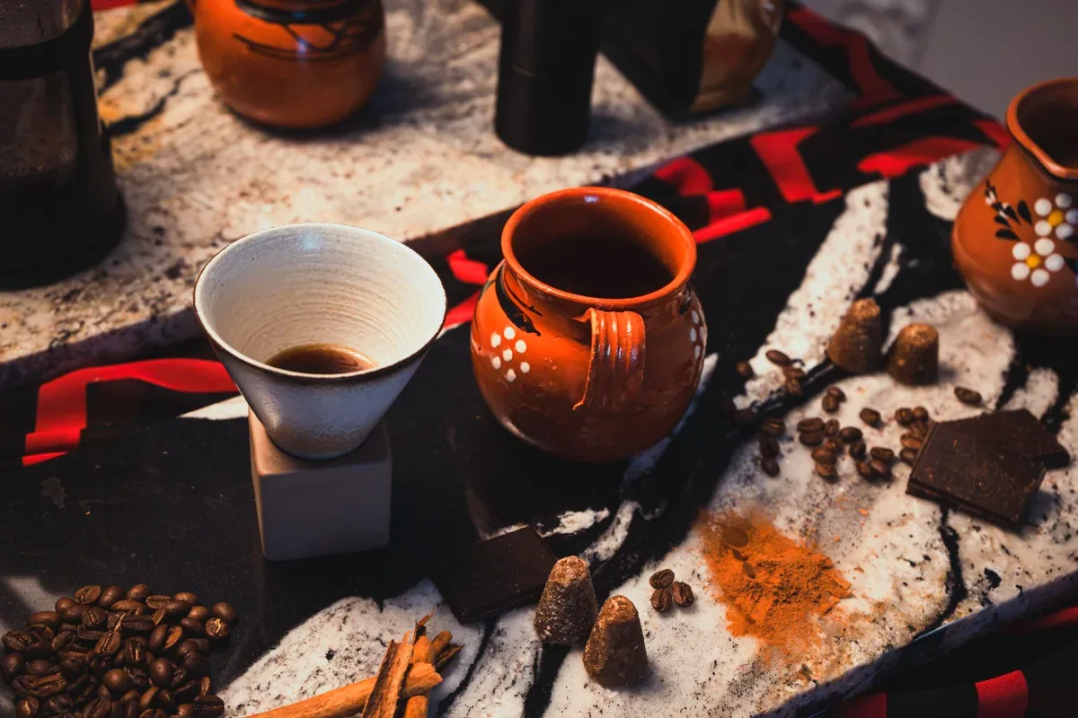 Tazas de barro, granos de café, cacao y especias sobre una mesa