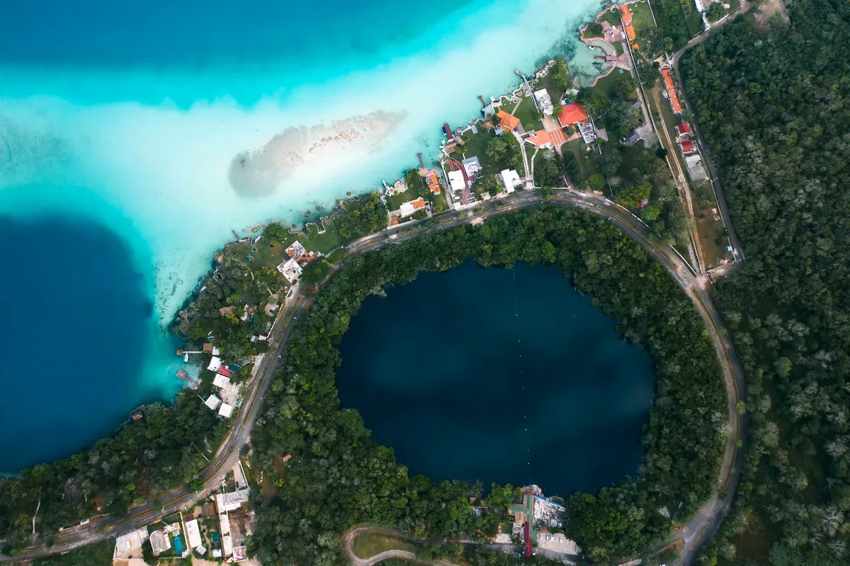 Vista aérea de un cenote circular junto a una laguna